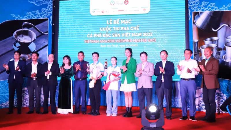 Hai thí sinh đoạt giải Nhất Cuộc thi pha chế cà-phê đặc sản Việt Nam năm 2023 Trương Thị Thiện và Phạm Ngọc Thạch chụp hình với các đồng chí lãnh đạo tỉnh Đắk Lắk và Ban tổ chức cuộc thi tại lễ bế mạc.