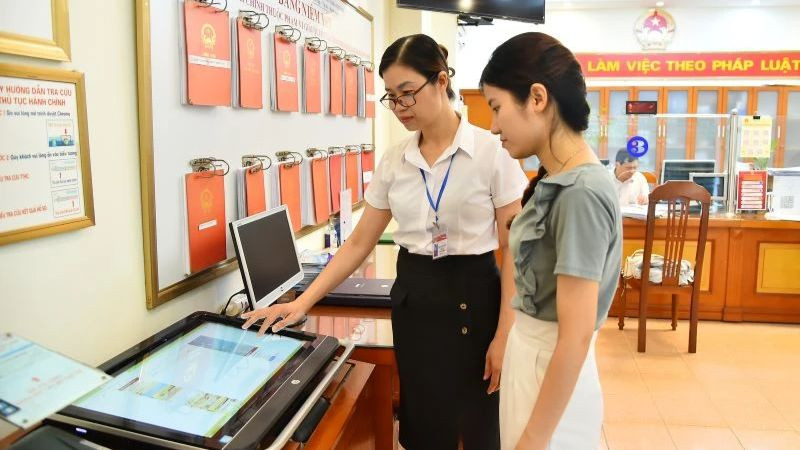 Cán bộ Ủy ban nhân dân phường Thanh Xuân Nam (quận Thanh Xuân, Hà Nội) hướng dẫn người dân thực hiện thủ tục hành chính trên môi trường mạng. (Ảnh: Thủy Nguyên/Báo Nhân Dân)