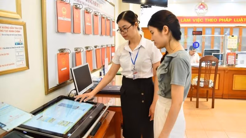 Cán bộ Ủy ban nhân dân phường Thanh Xuân Nam (quận Thanh Xuân, Hà Nội) hướng dẫn người dân thực hiện thủ tục hành chính trên môi trường mạng. (Ảnh: Thủy Nguyên/Báo Nhân Dân)