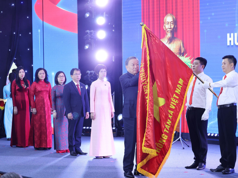 Tổng Bí thư Tô Lâm gắn Huân chương Hồ Chí Minh lên lá cờ truyền thống Thông tấn xã Việt Nam. Ảnh: Lâm Khánh - TTXVN