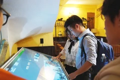 Các bạn trẻ trải nghiệm thư viện số hóa tại triển lãm.