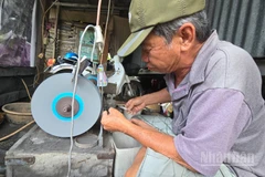 Ông Nguyễn Tấn Đức ngồi mài lưỡi câu.