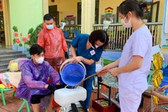 Cán bộ y tế phun hóa chất tiêu độc, khử trùng ở những nơi bị ngập lụt.