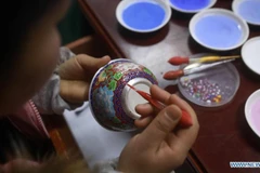 Nghệ nhân đang tráng men cho một chiếc bát bạc ở tỉnh Quý Châu, tây nam Trung Quốc. (Ảnh: Xinhua)
