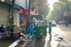Công nhân môi trường dọn dẹp, thu gom rác sau mưa bão trên phố Khâm Thiên (Hà Nội). 