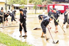 Các lực lượng Công an, quân sự dọn bùn sau khi nước lũ rút.