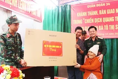 Bà Tô Thị Sửa vui mừng nhận quà của Quân đoàn 34 trong ngôi nhà mới.