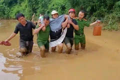 Công an xã Hữu Kiệm dìu sản phụ Kha Thị May vượt bùn lũ đến trạm y tế. (Ảnh: NGÔ HÙNG)