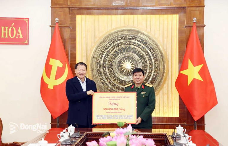 Đồng chí Vũ Hồng Văn, Bí thư Tỉnh ủy, Trưởng đoàn Đại biểu Quốc hội tỉnh Đồng Nai trao biểu trưng số tiền hỗ trợ gia đình cán bộ, chiến sĩ Bộ Chỉ huy Quân sự tỉnh Thanh Hóa bị ảnh hưởng do thiên tai, bão lũ. (Ảnh: PHONG SẮC)