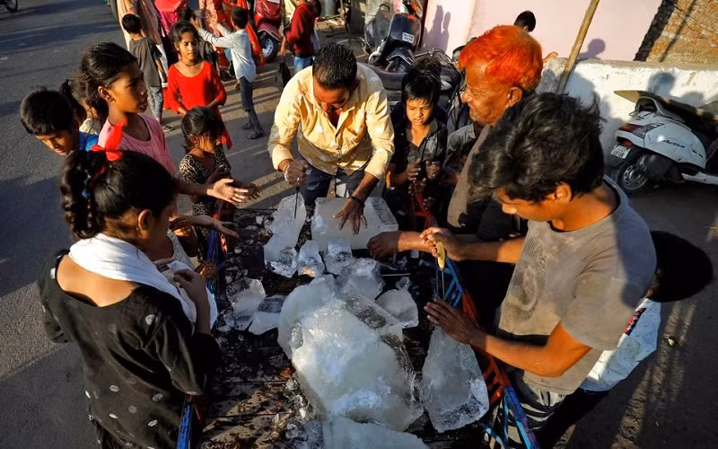 Người dân ở thành phố Ahmedabad, bang Gujarat, Ấn Độ vây quanh 1 xe chở đá để giảm nhiệt giữa nắng nóng gay gắt, ngày 28/4/2022. (Ảnh: Reuters)