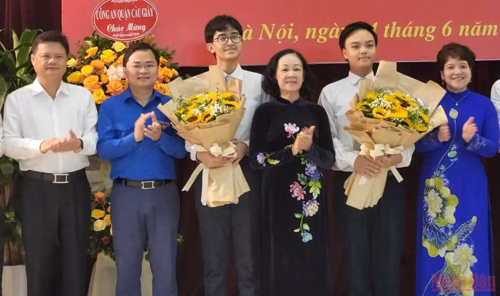 Đồng chí Trương Thị Mai tặng hoa hai đảng viên trẻ tại Trường THPT chuyên Hà Nội-Amsterdam. (Ảnh: SƠN BÁCH)