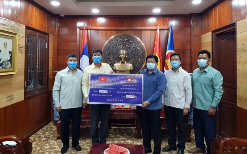Đồng chí Bouahong Khamha (phải) trao 150 triệu kíp Lào để ủng hộ, đóng góp vào Quỹ vaccine phòng, chống Covid-19, ngày 12-6.