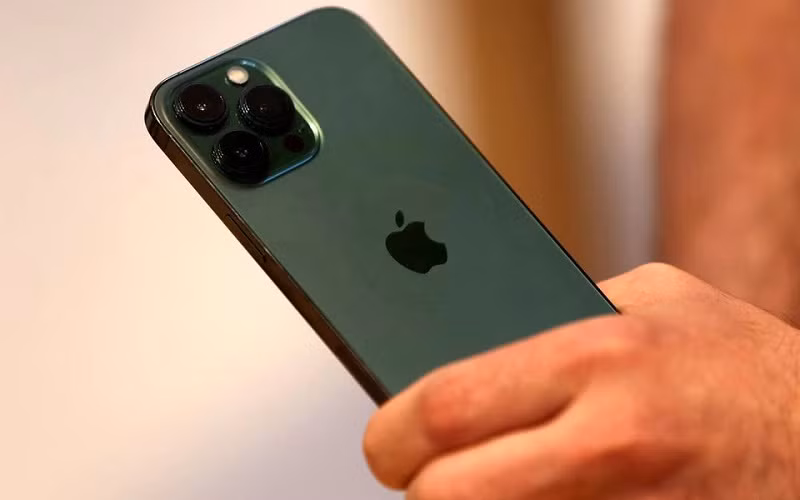 Một khách hàng cầm trên tay chiếc điện thoại iPhone 13 Pro màu xanh lục mới ngay sau khi nó được bày bán bên trong Apple Store tại Đại lộ số 5 ở Manhattan, New York City, tiểu bang New York, Mỹ, ngày 18/3/2022. (Ảnh: Reuters)