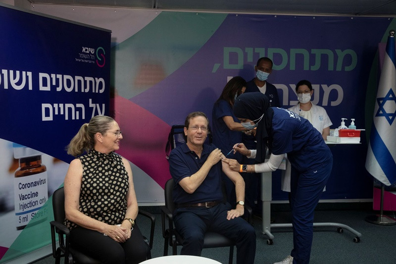 Ngồi bên phu nhân Michal, Tổng thống Herzog tiêm mũi vaccine thứ ba tại Trung tâm y tế Sheba ở khu vực Ramat Gan, gần Tel Aviv, ngày 30/7. (Ảnh: Reuters) ISRAEL -0