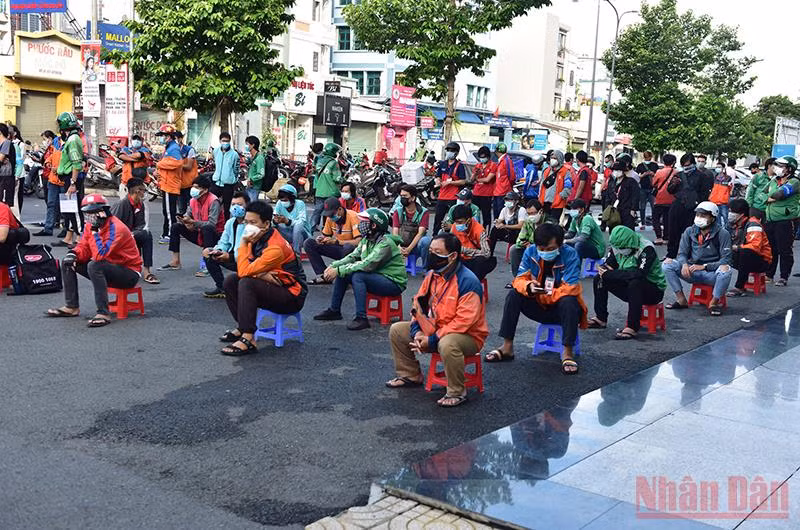 Các shipper xếp hàng dài chờ xét nghiệm tại một điểm ở phường 17, quận Gò Vấp. (Ảnh: QUÝ HIỀN)