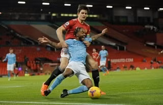 Sterling (áo xanh, Man City) tranh bóng với đội trưởng Man United H. Maguire.