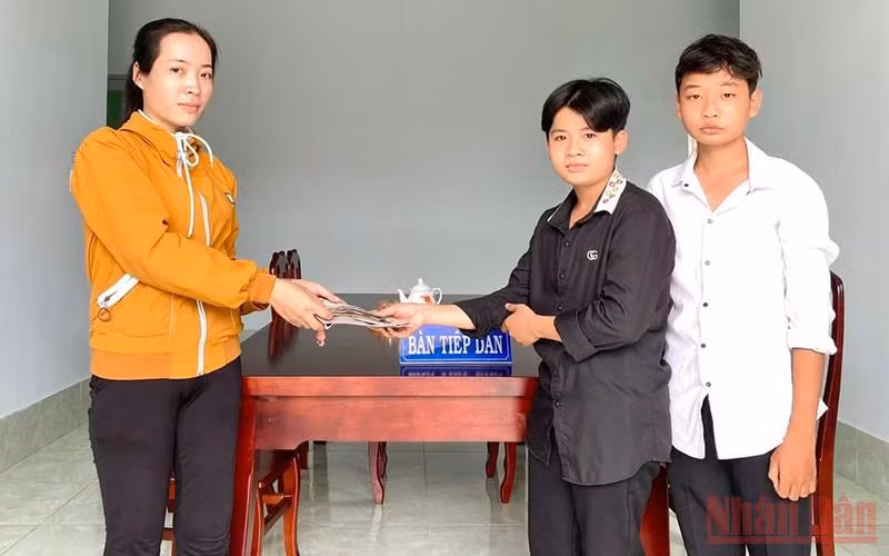 2 em học sinh trao lại chiếc ví cho người đánh rơi.