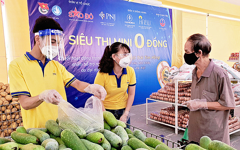 Nhân viên “Siêu thị mini 0 đồng” hướng dẫn, hỗ trợ người dân chọn mua hàng. “Siêu thị mini 0 đồng” tiếp sức người dân quận Hoàn Kiếm vượt dịch -0