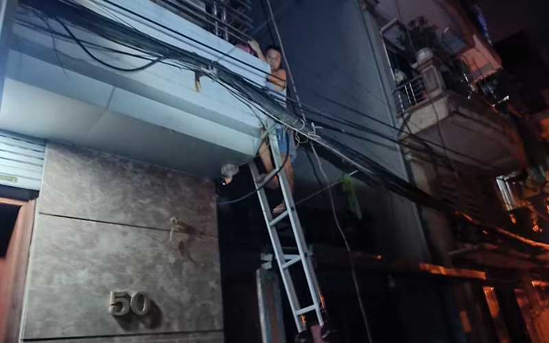 Lực lượng công an dùng thang đưa người mắc kẹt bên trong nhà thoát ra ngoài.