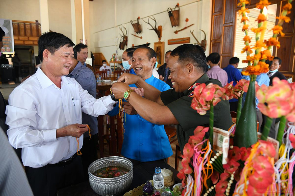 Nghi thức buộc chỉ cổ tay theo phong tục Tết cổ truyền Bunpimay của Lào với mong ước chúc nhau an khang, thịnh vượng, sức khỏe và may mắn. (Ảnh: THÀNH ĐẠT) Quan hệ hữu nghị đặc biệt Việt - Lào: Tết của bạn là Tết của mình -0
