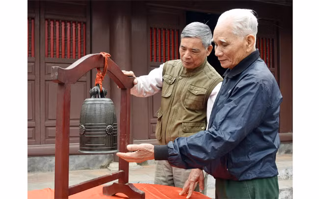 Người dân Đông Ngạc (Hà Nội) bên bảo vật quốc gia Chuông đình Nhật Tảo. Ảnh: TRẦN HẢI