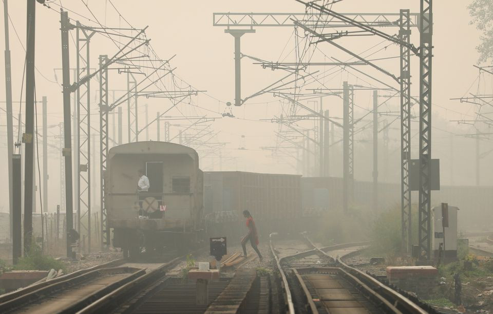 Một người phụ nữ băng qua đường ray khi tàu chở hàng chạy qua, vào một ngày sương mù ở New Delhi, Ấn Độ. Ảnh chụp ngày 12/11/2021. Ảnh: Reuters.