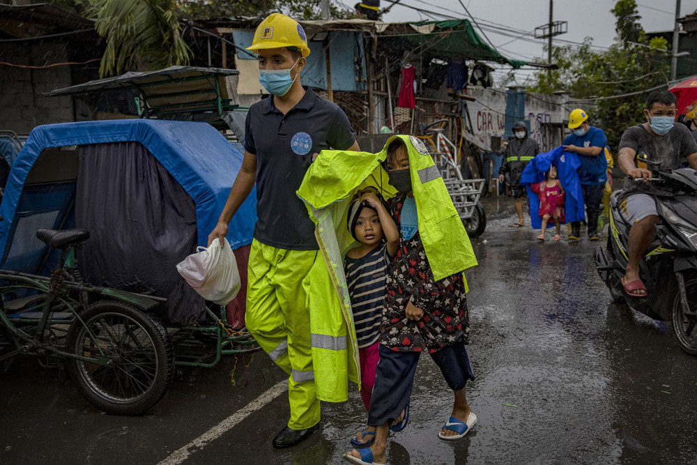 Nhân viên cứu nạn nhường áo mưa cho hai em nhỏ khi đưa các em di dời đến nơi an toàn tại Manila. (Ảnh: Getty Images) Goni -2