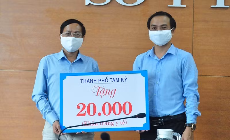 Phó Chủ tịch UBND TP Tam Kỳ Nguyễn Hồng Lai (bên phải) trao biểu trưng 20 nghìn khẩu trang cho Sở Y tế. 