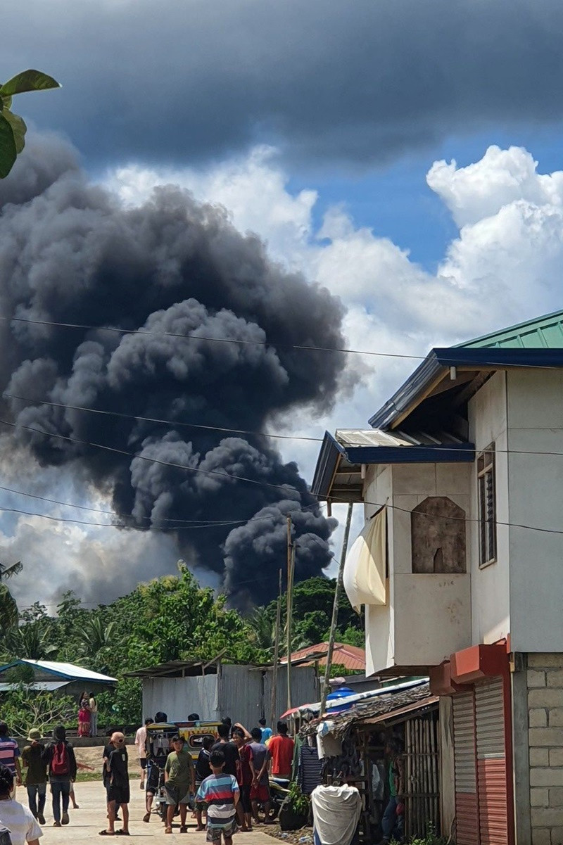 Người dân xem khói bốc lên từ hiện trường máy bay rơi. (Ảnh: Reuters) Rơi máy bay quân sự Philippines, ít nhất 17 người thiệt mạng -0