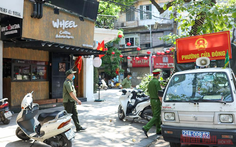 Công an phường Cửa Đông tuyên truyền nhắc nhở người dân phòng chống dịch. Ảnh: DUY LINH