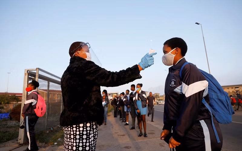 Kiểm tra thân nhiệt các học sinh trước khi vào lớp học ở thị trấn Langa, Cape Town, Nam Phi. (Ảnh: Reuters)