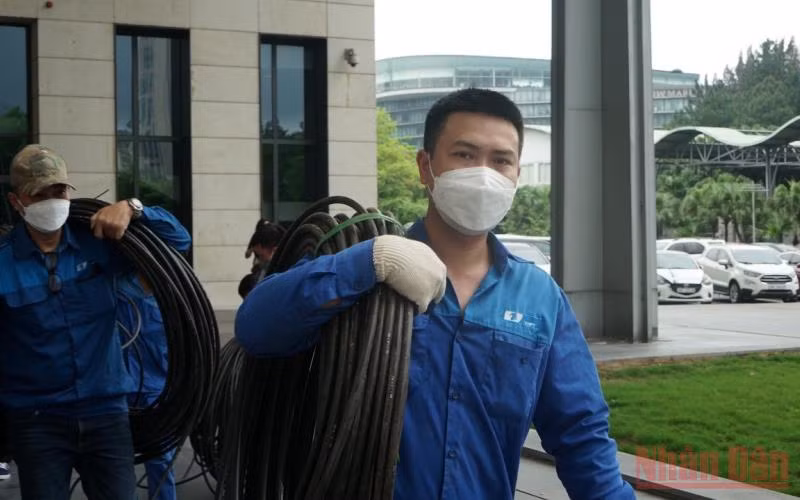 Anh Nguyễn Huy Ánh (bên phải) và đồng nghiệp thực hiện đấu nối đường tnternet đi quốc tế tại Trung tâm Hội nghị quốc gia.