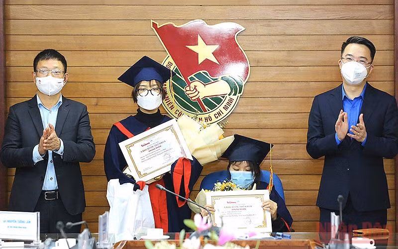 Đồng chí Nguyễn Tường Lâm, Bí thư Trung ương Đoàn (ngoài cùng bên phải) và ông Phùng Công Sưởng, Phó Tổng Biên tập Báo Tiền Phong trao học bổng “Nâng bước thủ khoa” năm 2021 tặng các nữ sinh Phí Thị Kim Oanh (ngồi ghế) và Nguyễn Hồng Minh.