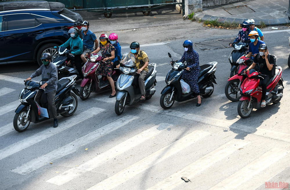 Trong lúc chờ đèn đỏ, dưới thời tiết nắng nóng như thiêu đốt, nhiều người đi đường cố len lỏi vào nơi bóng mát để tránh nóng. Người dân Hà Nội chống chọi với nắng nóng gay gắt -0