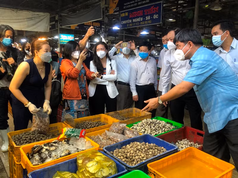 Thứ trưởng Nông nghiệp và Phát triển nông thôn Trần Thanh Nam (bên phải) trao đổi với tiểu thương chợ Bình Điền.