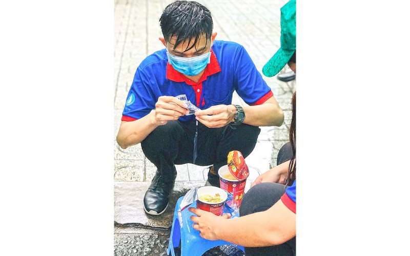 Những tình nguyện viên ướt sũng nước do vừa nhường ô, nhường áo mưa che cho thí sinh tranh thủ “nạp năng lượng” tại chỗ. 9-1622801422906.jpg