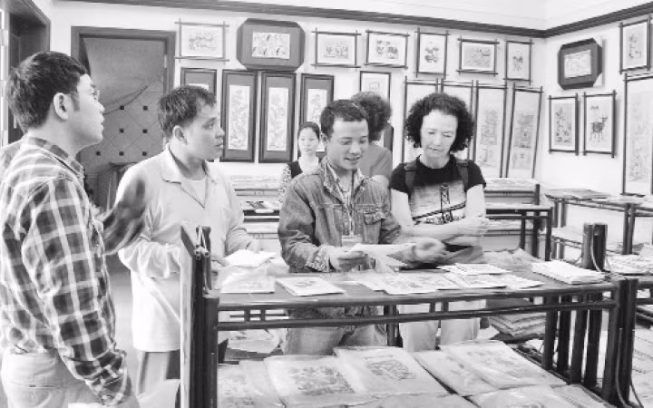 Nghệ nhân làng tranh Đông Hồ giới thiệu sản phẩm với khách. Ảnh: MINH HUỆ