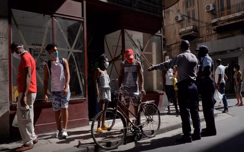 Cảnh sát hướng dẫn người dân tại Havana, Cuba, xếp hàng để mua thực phẩm. (Ảnh: Reuters)