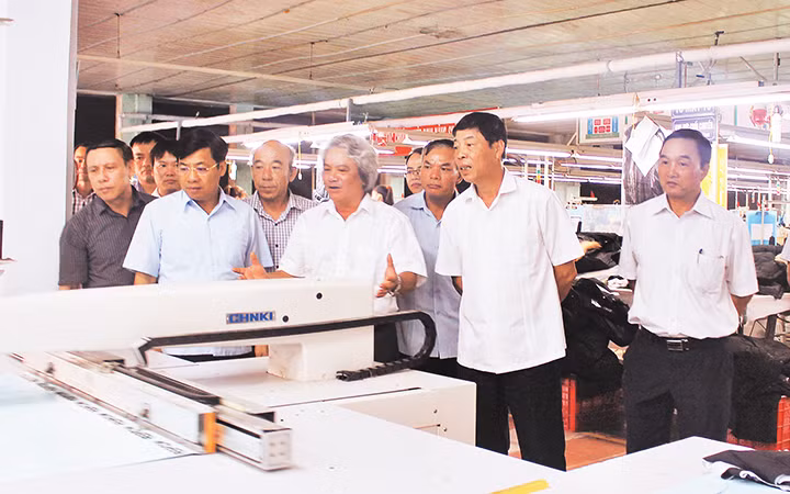 Anh hùng Lao động Nguyễn Hữu Phải (người thứ tư từ phải sang) giới thiệu hệ thống máy lập trình tự động trong ngành may. Ảnh: ĐỨC THANH 