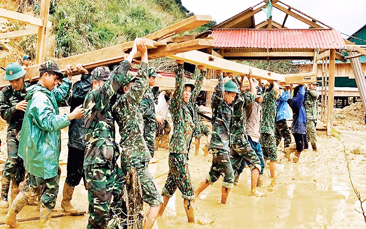 Cán bộ, chiến sĩ Đồn Biên phòng Ga Ry (Bộ Chỉ huy Bộ đội Biên phòng tỉnh Quảng Nam) giúp nhân dân huyện Tây Giang dựng lại nhà sau bão. Ảnh: PHAN TIẾN DŨNG