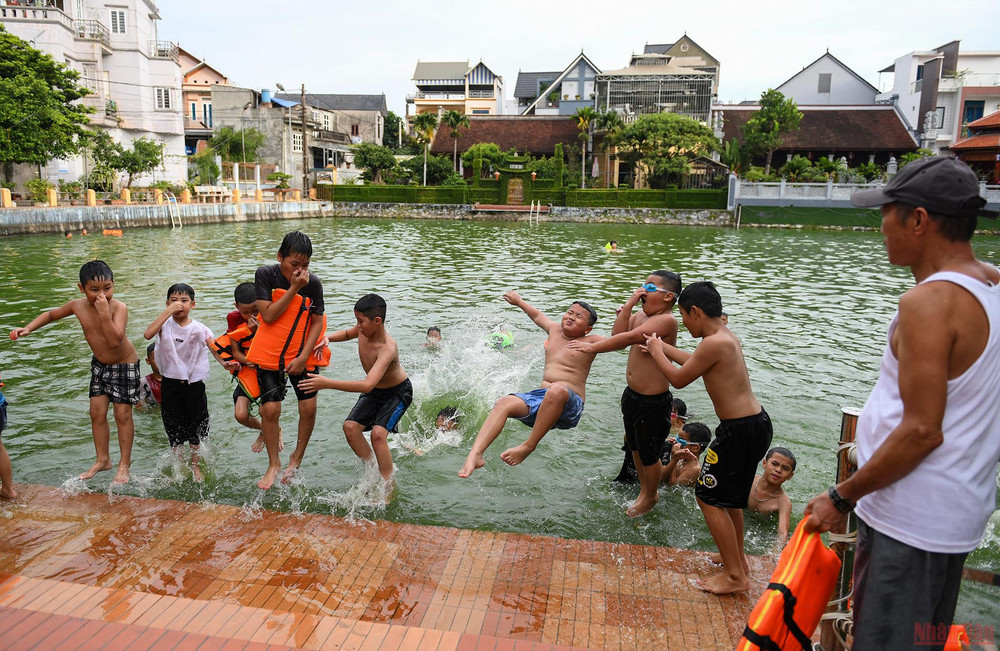 Người dân ngồi trên bờ luôn chăm chú quan sát con, em mình tắm dưới ao. 27.jpg -0