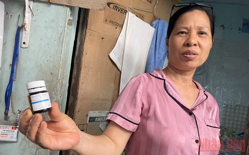 Bà Mai Thị Hường cùng lọ thuốc canxi dạng viên dùng tạm thay thế trong khi hết thuốc. (Ảnh: SƠN BÁCH)