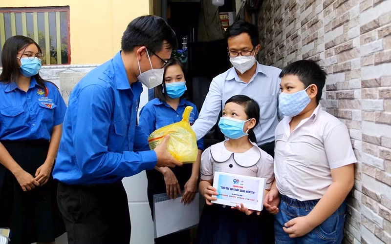 Ðoàn Thanh niên TP Hồ Chí Minh tặng máy tính bảng trong chương trình "Tuổi trẻ EVN thắp sáng niềm tin" cho trẻ mồ côi do dịch Covid-19 ở Quận 4. (Ảnh TTXVN)