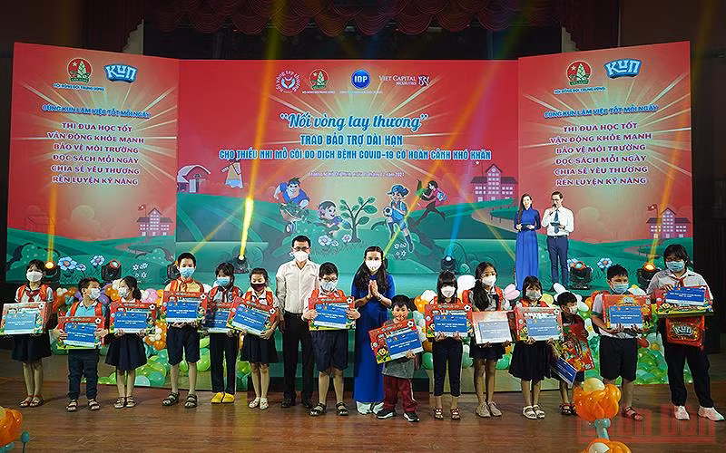 Đồng chí Nguyễn Phạm Duy Trang (áo xanh) và đại diện các đơn vị liên quan trao bảo trợ dài hạn tặng thiếu nhi mồ côi do đại dịch Covid-19.