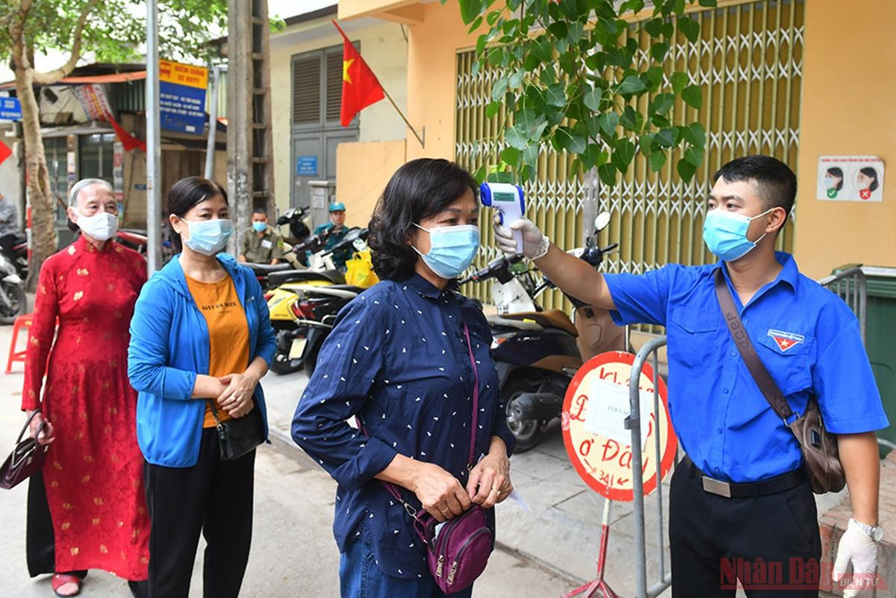 Đo thân nhiệt cho cử tri tại khu vực bỏ phiếu số 7, phường Đồng Tâm, quận Hai Bà Trưng. Ảnh: Thủy Nguyên Người dân Thủ đô trong “Ngày hội non sông” -0
