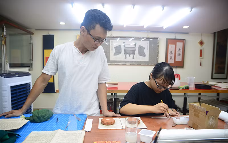 Hai vợ chồng anh Bùi Tiến Phúc phục chế cuốn Truyện Kiều tại Hán Nôm Đường.