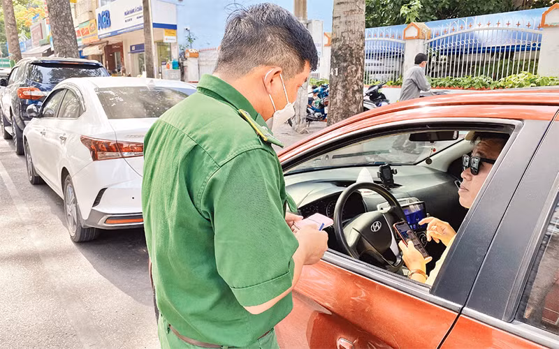 Nhân viên thu phí trên tuyến đường An Dương Vương, quận 5 nhắc nhở tài xế cài đặt app để thanh toán phí đỗ xe.
