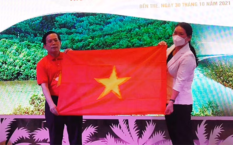 Phó Chủ tịch UBND tỉnh Bến Tre Nguyễn Thị Bé Mười nhận tượng trưng 10 nghìn lá cờ Tổ quốc từ lãnh đạo báo Người Lao Động.