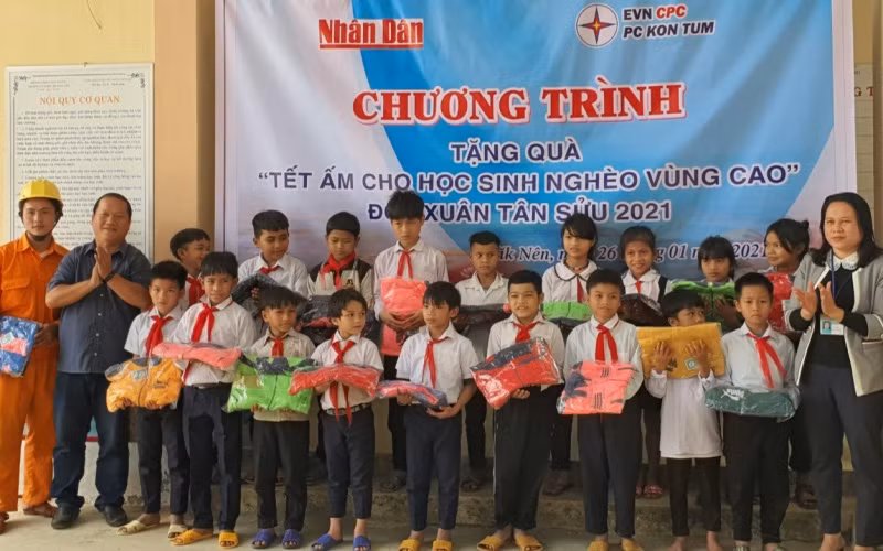 Phóng viên Báo Nhân Dân cùng đại diện Công ty Điện lực Kon Tum trao áo ấm cho các em học sinh Trường PTDT bán trú tiểu học Đắk Nên.