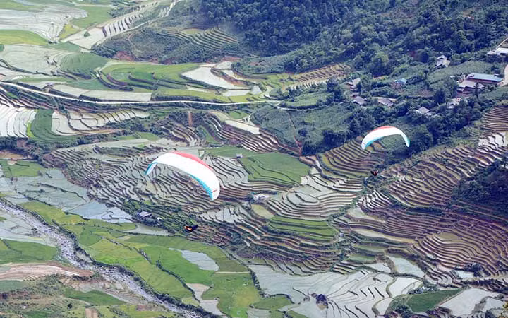 Du khách trải nghiệm bay dù lượn trên ruộng bậc thang huyện Mù Cang Chải, tỉnh Yên Bái trong mùa nước đổ. (Ảnh: ĐỨC TƯỞNG)